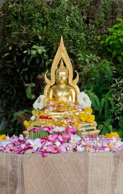 Buddha statue covered with flower petals after being cleansed an clipart