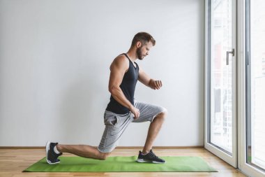 Yakışıklı genç adam evde akıllı bir saatle çalışıyor.