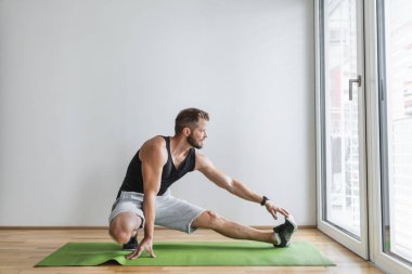 Yakışıklı genç adam evde akıllı bir saatle çalışıyor.