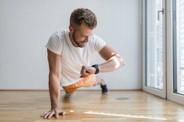 Yakışıklı genç adam evde akıllı bir saatle çalışıyor.