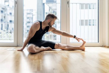 Genç yakışıklı adam evde yoga yapıyor.