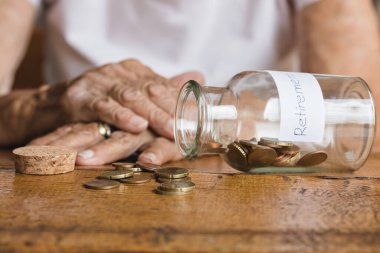 Emekli yaşlı bir kadın ve birikimleri kavanozda.