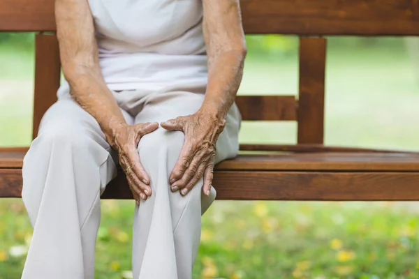 Senior Vrouw Zit Bank Houdt Haar Pijnlijke Knie Vast — Stockfoto