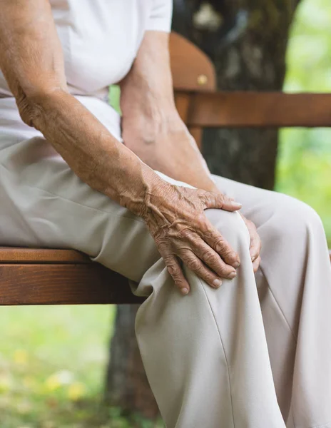 Senior Vrouw Zit Bank Houdt Haar Pijnlijke Knie Vast — Stockfoto