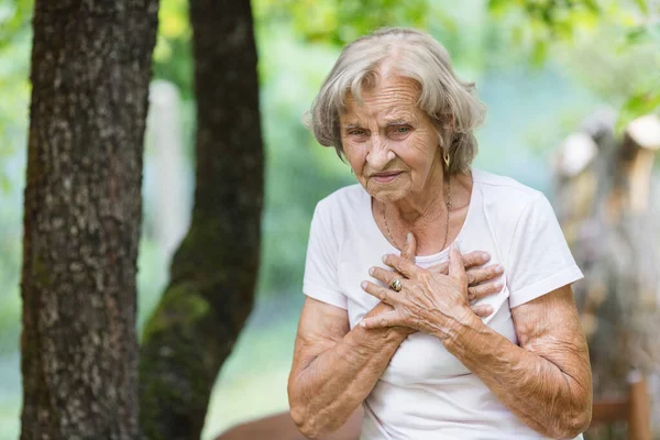 Elderly Woman Outdoors Heart Pain Holding Her Chest — Stockfoto