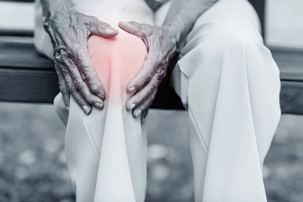 Senior Vrouw Zit Bank Houdt Haar Pijnlijke Knie Vast — Stockfoto