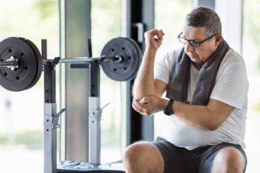 Spor salonunda dirsek ağrısı olan son sınıf öğrencisi.