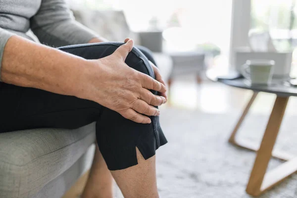 Senior Vrouw Zit Bank Houdt Haar Pijnlijke Knie Vast — Stockfoto