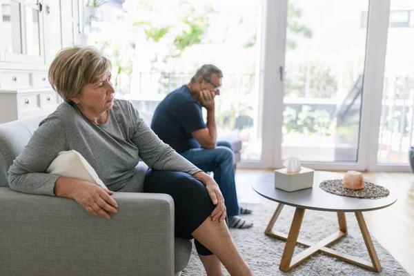 Upset senior couple at home in living room having an argument