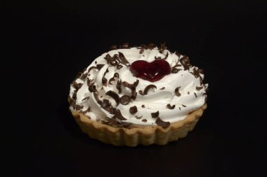 Siyah arka planda beyaz kremalı, çikolatalı ve marmelatlı kek sepeti