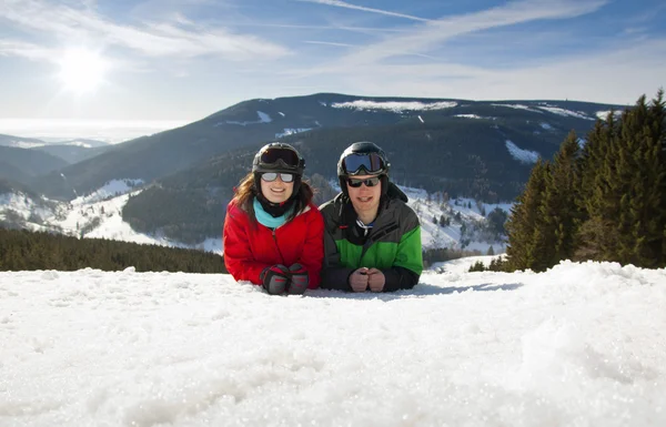 Joven pareja feliz yaciendo en montañas nevadas. Vacaciones deportivas de invierno — Foto de Stock