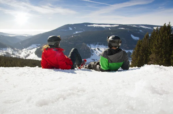 Joven pareja feliz yaciendo en montañas nevadas. Vacaciones deportivas de invierno —  Fotos de Stock