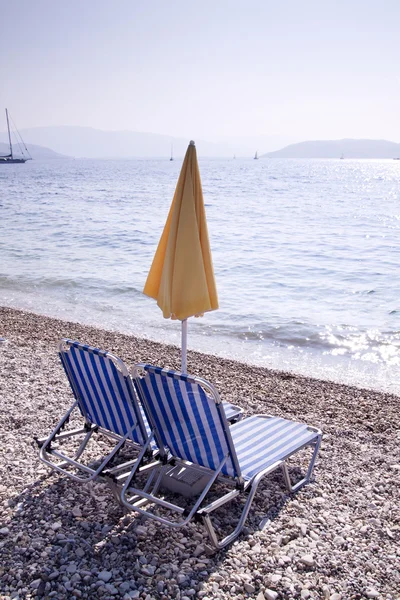 Sun lounger and umbrella on empty sandy beach — Stock Photo, Image