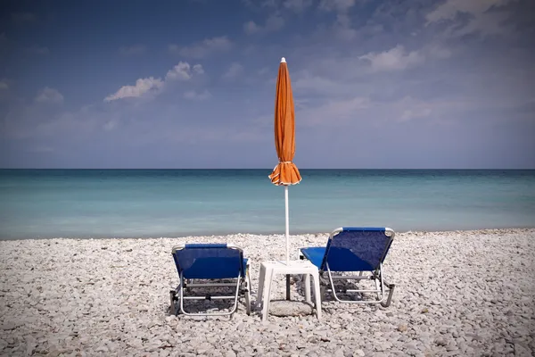 Sun lounger and umbrella on empty sandy beach — Stock Photo, Image