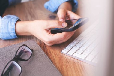 Ahşap ofis masasında akıllı telefon maketi kullanarak iş kadınlarının ellerini görüntüledik. Grafik görüntüleme için boş ekran cep telefonu
