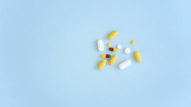 Çeşitli ilaç hapları, haplar ve kapsüller mavi arka planda.