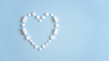 Çeşitli ilaç hapları, haplar ve kapsüller mavi arka planda.