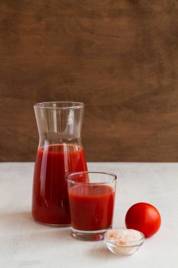 Bardakta domates suyu. Pembe tuzlu domates suyu. Fotokopi alanı olan beyaz bir arka planda izole edilmiş domates suyuyla sağlıklı bir içecek. dikey