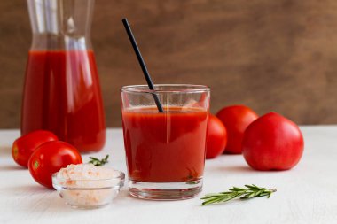 Domates suyu ve taze domates. Bir bardak pembe tuzlu domates suyu. Fotokopi alanı olan beyaz bir arka planda izole edilmiş domates suyu bardağında sağlıklı bir içecek.