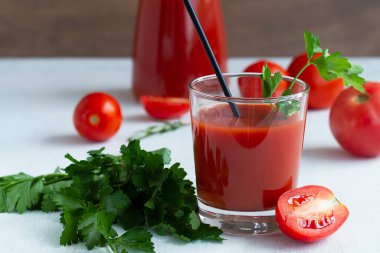 Domates suyu ve domates. Maydanozlu domates suyu. Fotokopi alanı olan beyaz bir arka planda izole edilmiş domates suyu bardağında sağlıklı bir içecek..