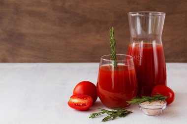 Beyaz arka planda domates suyu ve taze domates. Bir bardak biberiyeli domates suyu ve masada fotokopi alanı olan tuz.