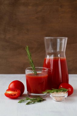 Taze domates suyu, tuzlu ve biberiyeli. İçindekilerle birlikte Bloody Mary kokteyli. Beyaz arka planda izole edilmiş bir bardakta votka ve domates suyu ile alkollü içecek. kopyalama alanı. dikey