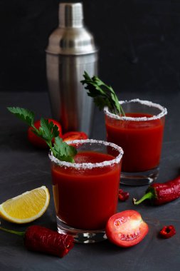 Tuzlu domates suyu. İçindekilerle birlikte Bloody Mary kokteyli. Siyah arka planda izole edilmiş bir bardakta votka ve domates suyu ile alkollü içecek. Masada biberli vampir kokteyli. kopyalama alanı. dikey