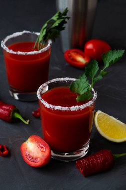 Biberli, baharatlı, tuzlu ve sarı limonlu domates suyu ve fesleğen. Bloody Mary kokteyli. Votka, vampir kokteyli ve siyah arka plandaki malzemelerle alkollü içecek..