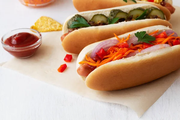 Beyaz masada havuçlu ve cipsli ev yapımı sosisli sandviç. Lokantanın beyaz arka planında turşu, sos ve ketçaplı lezzetli sosisli sandviç. Fotokopi alanı olan fast food kavramı.