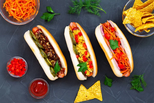 Farklı malzemeli sosisler: turşu, kızarmış soğan, domates ve siyah arka planda fotokopi alanı olan havuç. Düz yat. Fast food konsepti üst görünüm