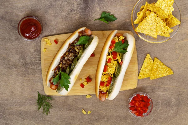 Farklı malzemeli ev yapımı lezzetli sosisler: turşu, kızarmış soğan, domates ve havuç, ahşap arka planda fotokopi alanı olan yeşil havuç. Düz yat. Fast food konsepti üst görünüm.