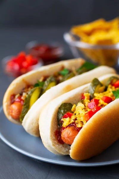 Hardallı sosisli, turşulu sosisli, kızarmış soğanlı, sosisli ve ketçaplı bir restorandaki ahşap tepside. Gri tabakta sosisli sandviç. Fotokopi uzayı ile fast food konsepti. dikey