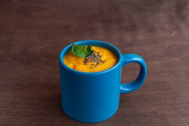 Koyu ahşap arka planda mavi bardakta yeşil kabak kremalı çorba. Vejetaryen çorbası kremalı püre, kıtır ekmek ve fotokopi alanı..