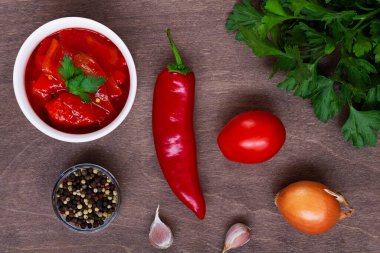 Domates leçosu ve içinde malzemeler olan tatlı kırmızı biber manzarası. Macar mutfağının ulusal menüsü biber ve domatesli, beyaz kasede yeşillikler. Macar yemeği. Boşluğu kopyala. Düzleştir