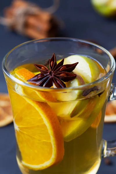 Kapalı bir bardak sıcak şarap. Noel sıcak beyaz şarap, portakal, bal, tarçın çubukları ve siyah arka planda baharat bulunan yıldız anason. Baharatlı sıcak içecek. Boşluğu kopyala