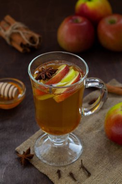 Taze elma ve bal ile elma şarabı. Baharatlı sıcak meyve çayı: tarçın, kardamon, anason, ahşap masadaki karanfil. Çuval bezli Noel içkileri. sıcak şarap. dikey
