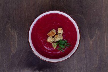 Kırmızı çorba. Sebzeli sebze çorbası. Kahverengi ahşap arka planda kıtır ekmekli pancar kremalı çorba. Sağlıklı beslenme yemeği. Düz yerde, üst tarafta. Boşluğu kopyala
