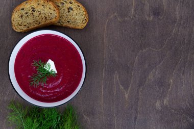 Kırmızı pancar çorbası. Sebzeli sebze çorbası. Kahverengi ahşap zemin üzerinde beyaz kremalı pancar kremalı çorba. Sağlıklı bir diyet yemeği. Düz yerde, üst tarafta. Boşluğu kopyala