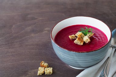 Kırmızı pancar çorbası. Sebze çorbası, sebze ve kızarmış ekmek. Ahşap zemin üzerinde ekmek olan gri pancar kremalı çorba kasesi. Fotokopi alanı ile sağlıklı diyet öğle yemeği.