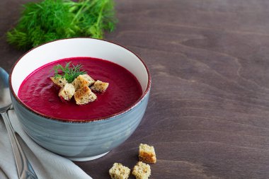 Sebzeli, sebze çorbası ve kızarmış ekmek. Ahşap zemin üzerinde ekmek olan gri pancar kremalı çorba kasesi. Fotokopi alanı ile sağlıklı diyet öğle yemeği.
