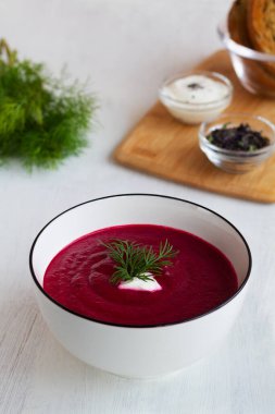 Kırmızı pancar çorbası. Yeşil sebzeli ev yapımı kırmızı sebze çorbası. Beyaz arka planda ekmek ve baharatlı pancar kremalı çorba. Fotokopi alanı olan sağlıklı bir diyet yemeği. dikey