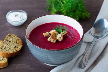Ekmekli bir kase çorba. Yeşil sebze çorbası ve kızarmış ekmek. Tahta arka planda ekmek ve kaşıkla pancar kremalı çorba kasesi. Fotokopi alanı ile sağlıklı diyet öğle yemeği.