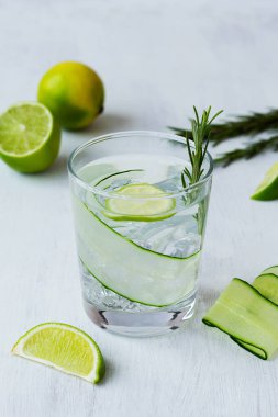 Limonlu kokteyl. Limonlu ve biberiyeli salatalık suyu. Beyaz masada limon dilimleri ve salatalıklı bir bardak limonata. Fotokopi odalı soğuk alkol içecekler. Detoks suyu. yaz