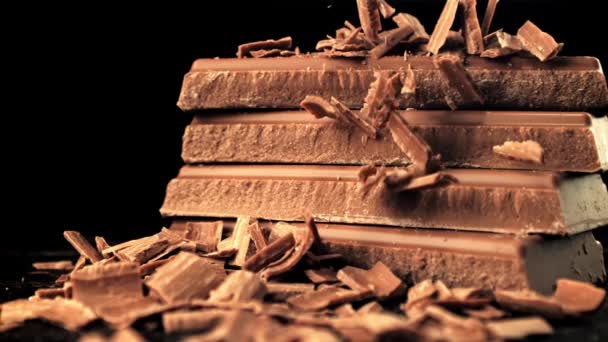 Super slow motion tomber morceaux de chocolat au lait. Sur fond noir. — Video