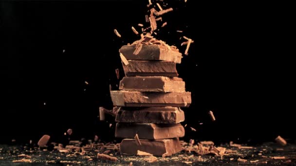 Σούπερ αργή κίνηση πτώση του τριμμένου, σοκολάτα γάλακτος σε μια πυραμίδα από φέτες σοκολάτας. — Αρχείο Βίντεο