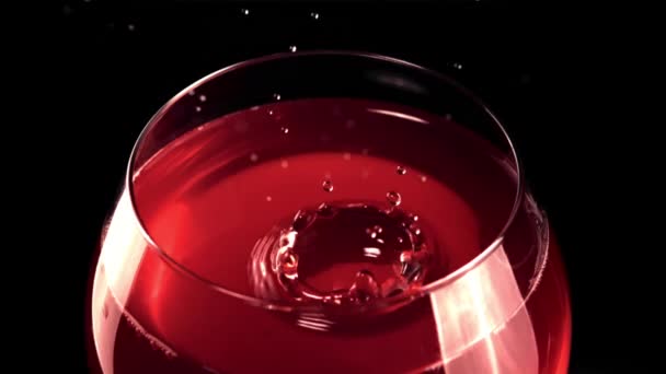 Super rallentatore goccia con spruzzi cade in un bicchiere di vino. Girato su una telecamera ad alta velocità a 1000 fps. — Video Stock