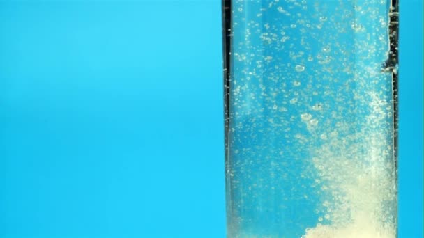 In einem Glas Wasser sprudelnde Tablette mit Luftblasen. Gefilmt wird Zeitlupe 1000 fps. — Stockvideo