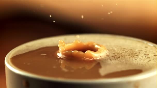 Een druppel valt in een kopje koffie met melk met spetters. Gefilmd is slow motion 1000 fps. — Stockvideo