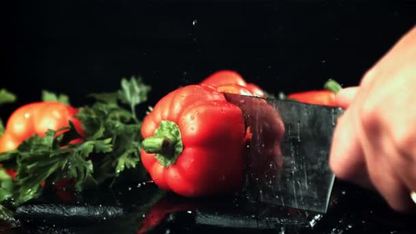 Ένα αντρικό χέρι κόβει μια γλυκιά πιπεριά στα δύο με ένα μαχαίρι. Ταινία είναι αργή κίνηση 1000 καρέ το δευτερόλεπτο. — Αρχείο Βίντεο