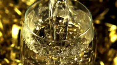 Altın şampanya hava kabarcıklı bir bardağa doluyor. Saniyede 1000 kare yavaş çekimde çekiliyor..